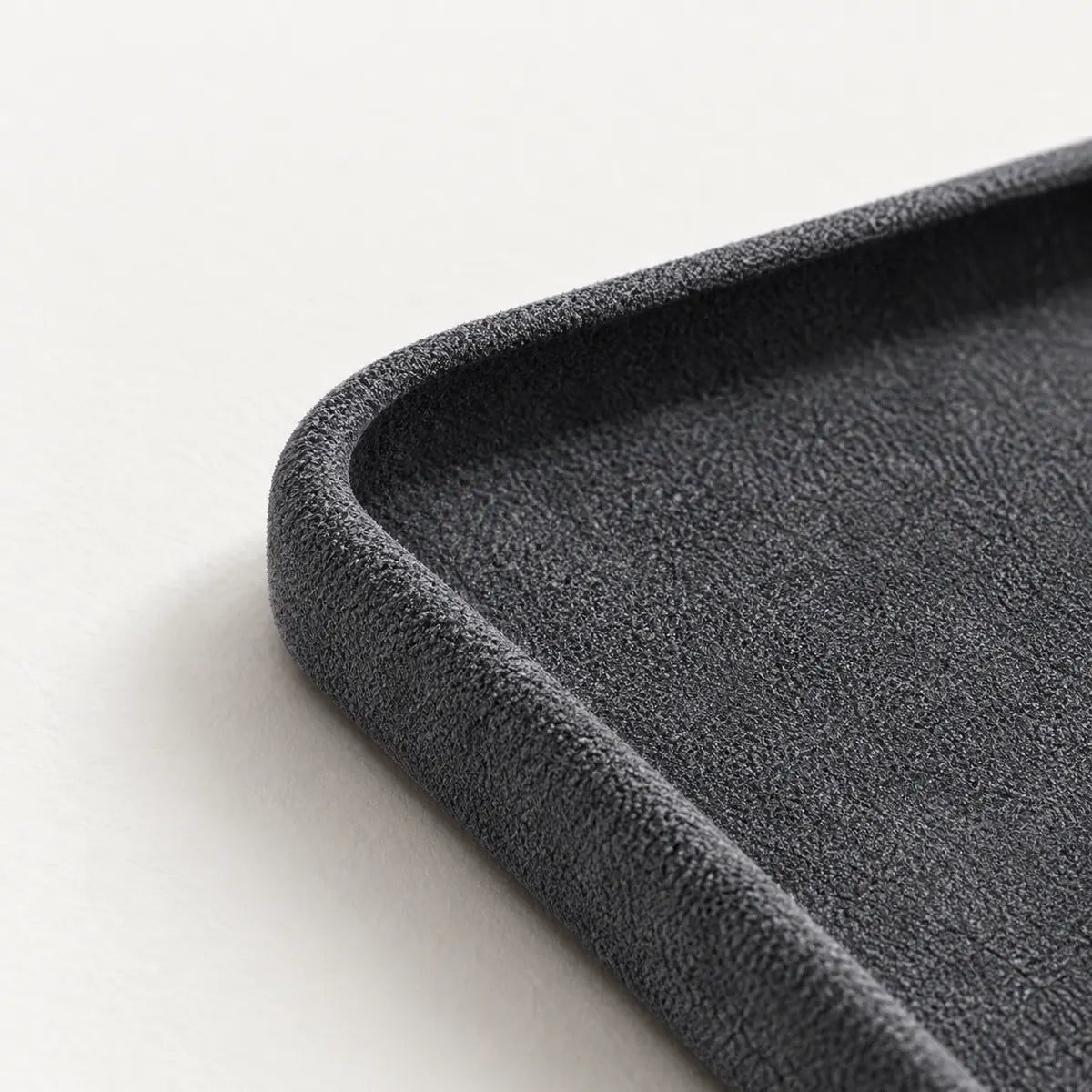 Close view of the soft fabric lining and rounded corner of a charcoal phone case.