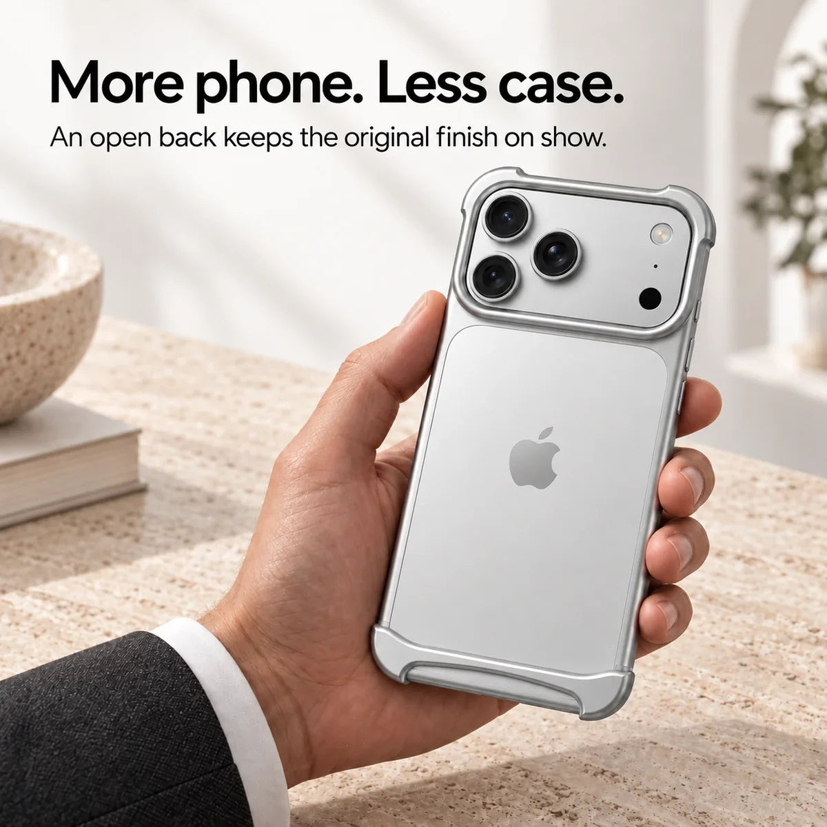 Silver metal phone bumper held above a pale stone desk, showing the exposed phone back #color_Titanium Silver