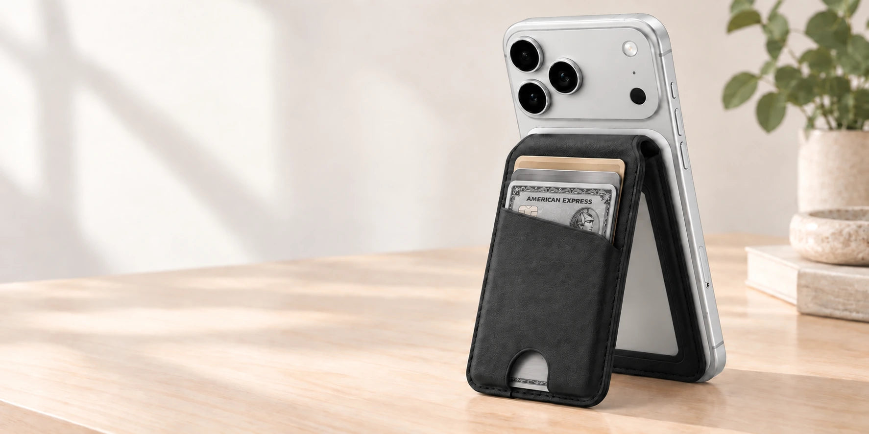 Black folding magnetic wallet holding premium silver cards and supporting a silver phone.