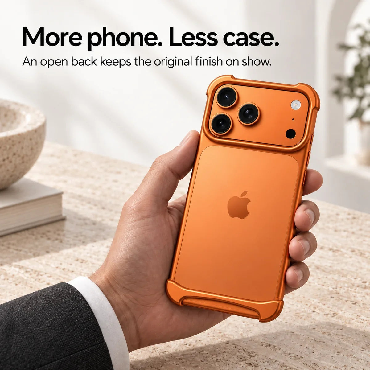 Orange metal phone bumper held above a pale stone desk, showing the exposed phone back #color_Cosmic Orange